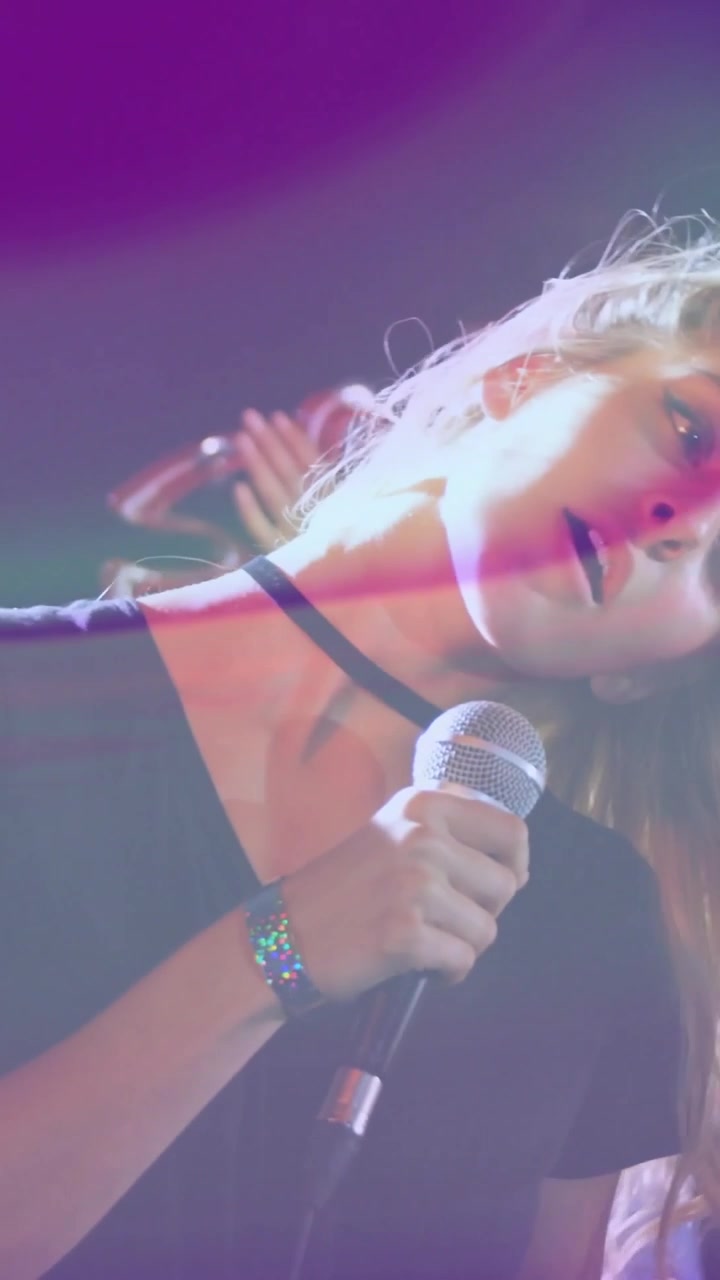 Vertical video: Lead singer hearing band cue, singing into mic for music gig while lights streaking