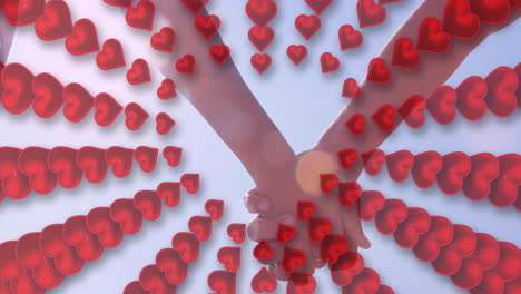 animation of hearts over hands of caucasian couple