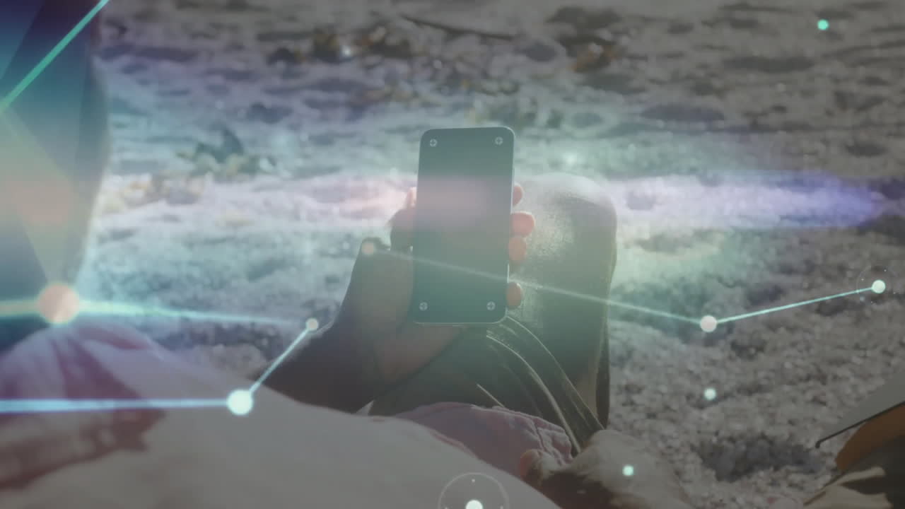 Person holding smartphone on beach with digital network animation overlay