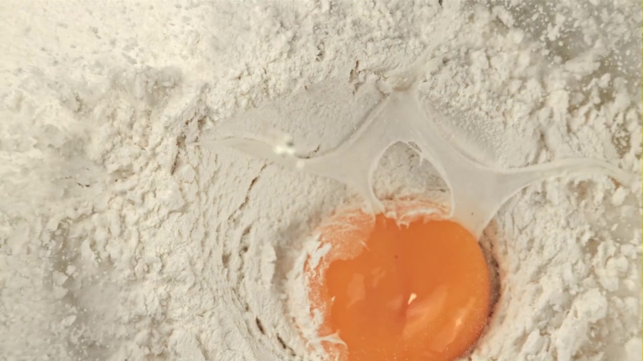 Slow Motion Egg Yolk Falling into White Flour