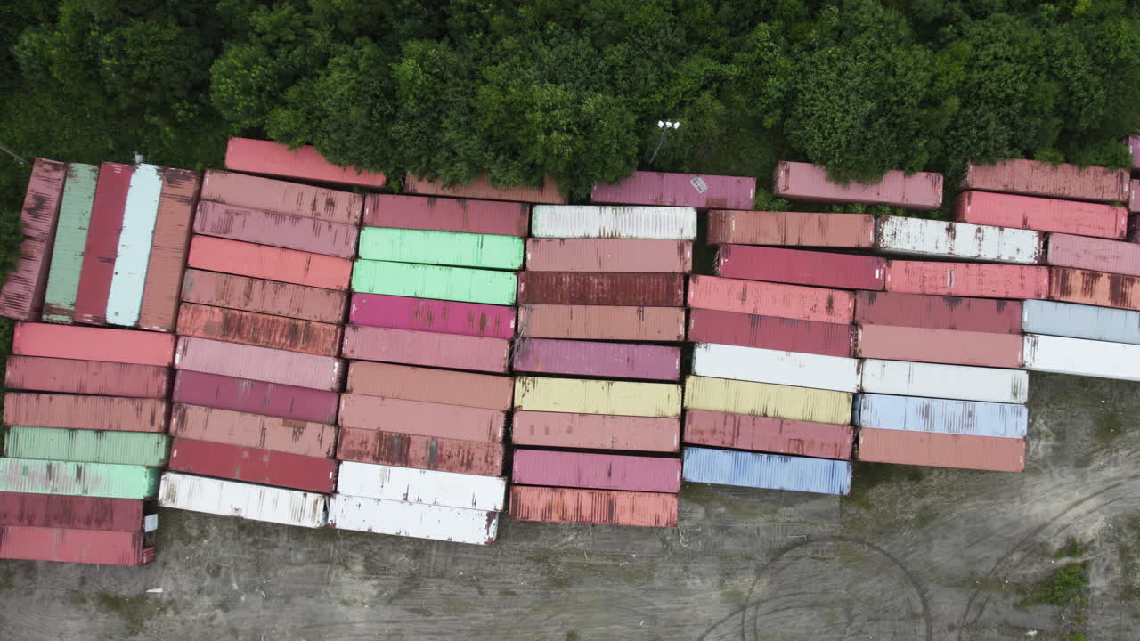Rows of colorful shipping containers stacked outdoors with green vegetation nearby