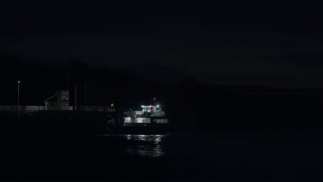 a night scene of a brightly lit ferry boat leaving an old victorian pier, with reflections of the lights shimmering on the calm water