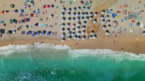 Aerial-drone-bird's-eye-view-over-tourists-sunbathing-visiting-Gjipe-beach,-Albania-on-a-sunny-day