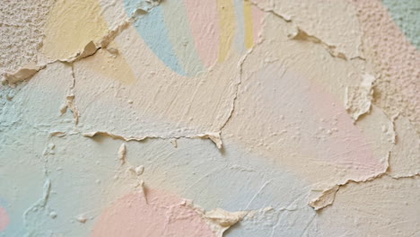 close-up of peeling paint on a wall with pastel colors