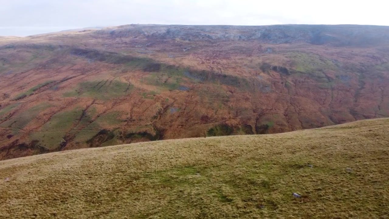 Vista aerea con drone in rapido movimento del paesaggio montano di Brecon Beacons con rocce e terreno accidentato 4K.