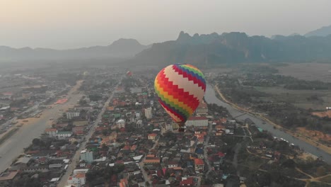 Flying-around-hot-air-balloon-above-vang-vieng-Laos-with-sunrise,-aerial