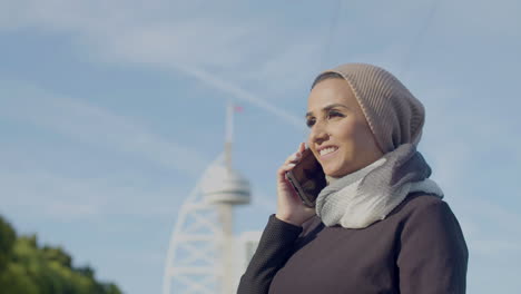 mujer árabe feliz hablando con su novio por teléfono al aire libre