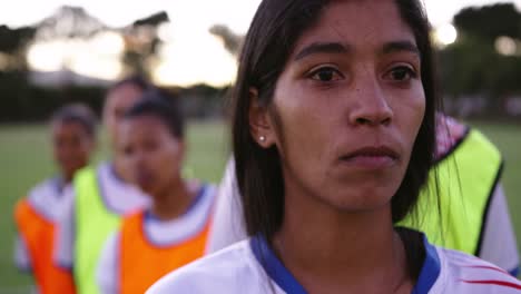 Female-soccer-player-standing-in-front-of-her-diverse-female-soccer-team-on-field.-4k