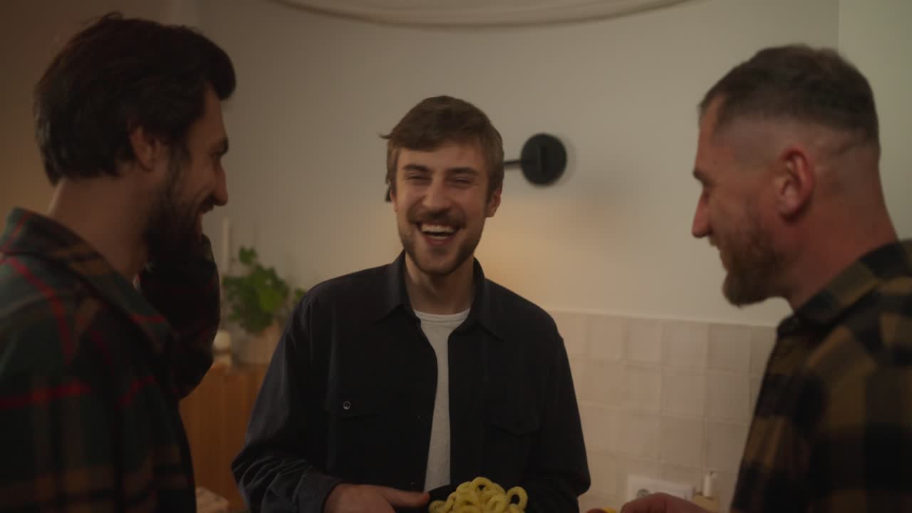 Venner nyder snacks i køkkenet