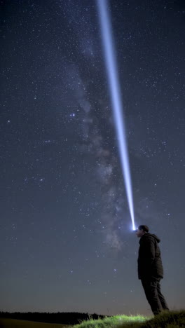person with a beam of light reaching the milky way at night