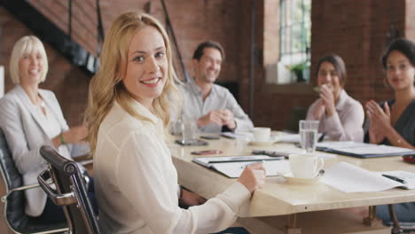 portrait of a confident young business woman  at boardroom table in slow motion turning around and smiling