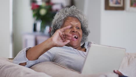 mujer afroamericana de alto nivel agitando y soplando besos mientras hace una videollamada en una tableta digital