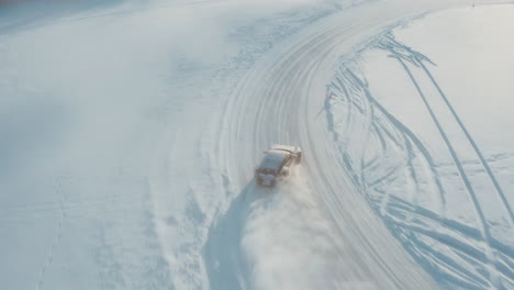 drone footage of porsche carrera 2020 911 4s drifting on frozen lake in circle shaped track. winter morning time, lot of snow particles, sunlight visible. filmed in 4k resolution. top camera angle.