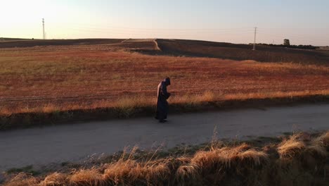 a shot from low height following sideways a monk walking on a dirt road