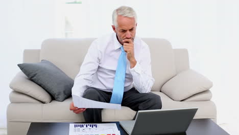 businessman working on the couch and smiling at camera