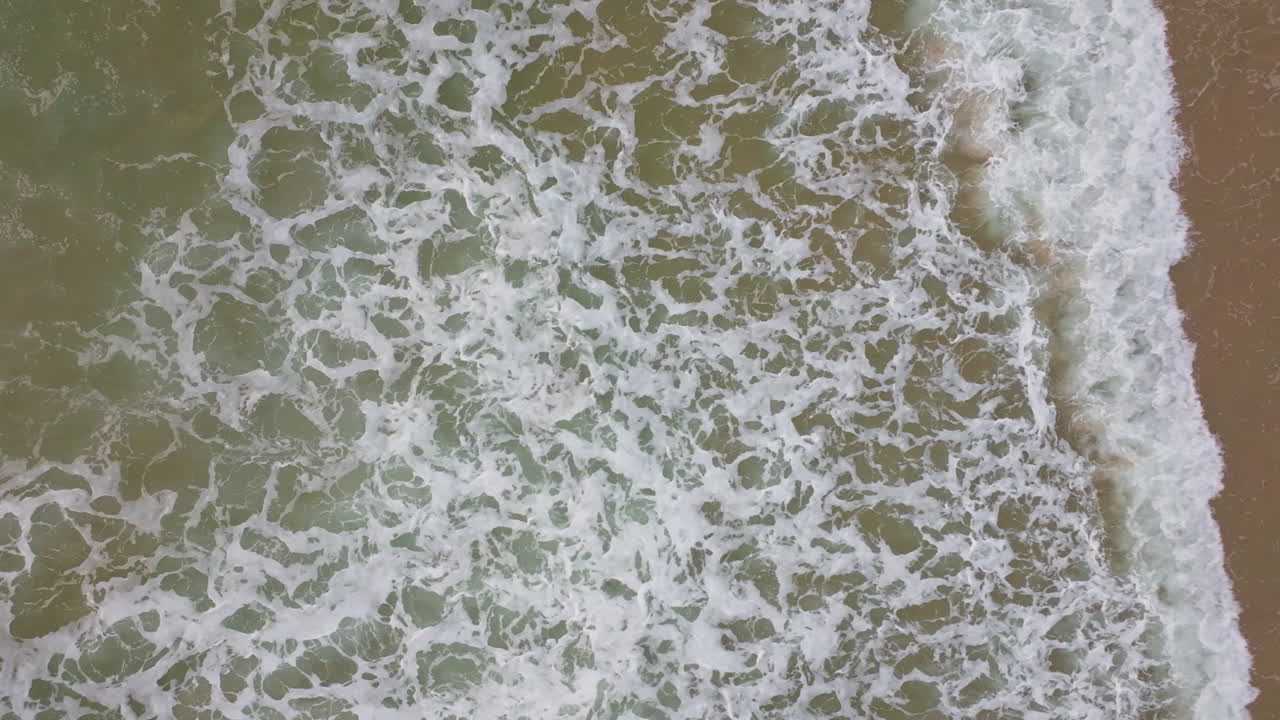 vista aérea de las olas que se estrellan en una playa de arena