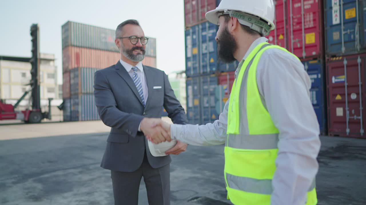 empresario senior o ejecutivo apretón de manos saludando con ingeniero masculino en el patio de carga de contenedores. socios de negocios saludando con apretones de manos, tratando de trabajar o acordar inversión juntos. colaboración en proyectos o negocios.