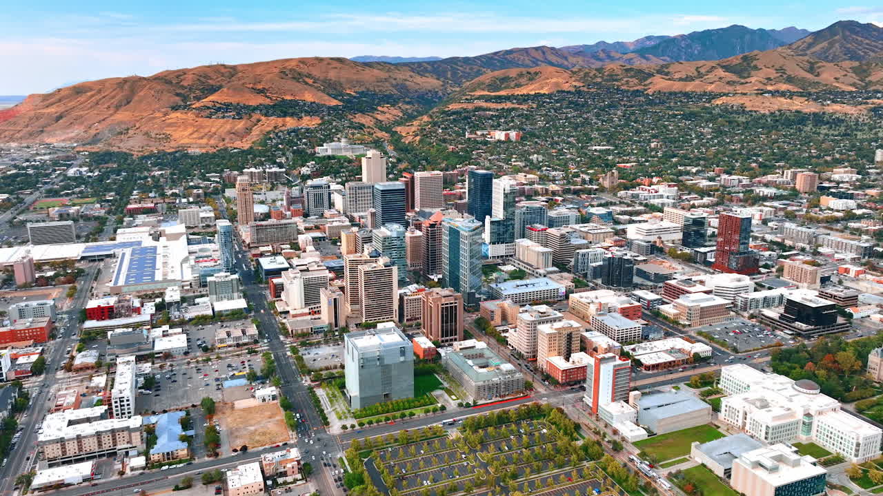 Cityscape of modern Salt Lake City from drone. Approaching the mountains with urban area on the slope