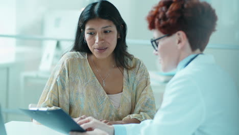 beautiful hispanic woman talking with female doctor in clinic