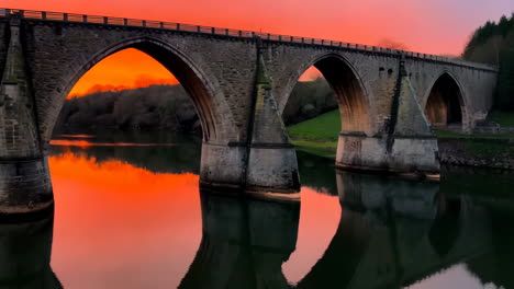 stone arch bridge at sunset with vibrant reflections