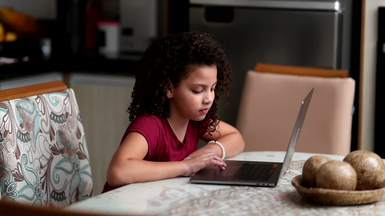 Child using laptop computer at home, little child staring at screen browsing internet