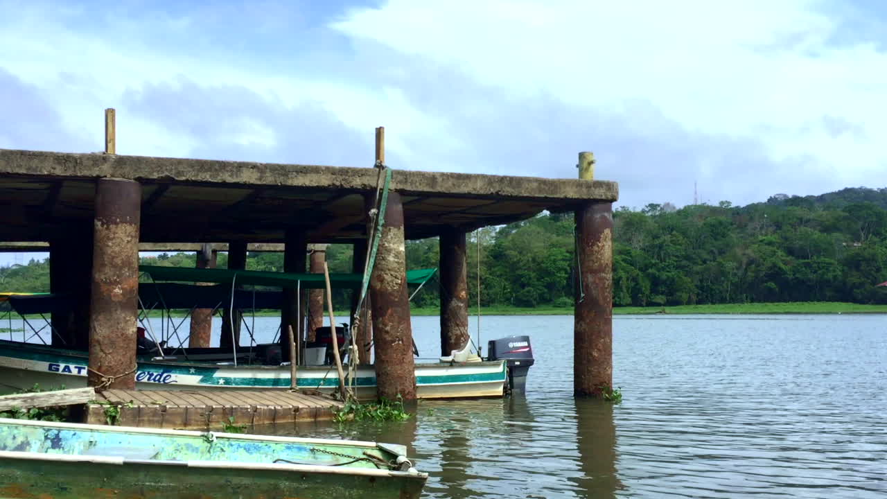 día soleado, cielos azules, de un muelle, aguas plácidas y algunos botes en el lago gamboa en panamá