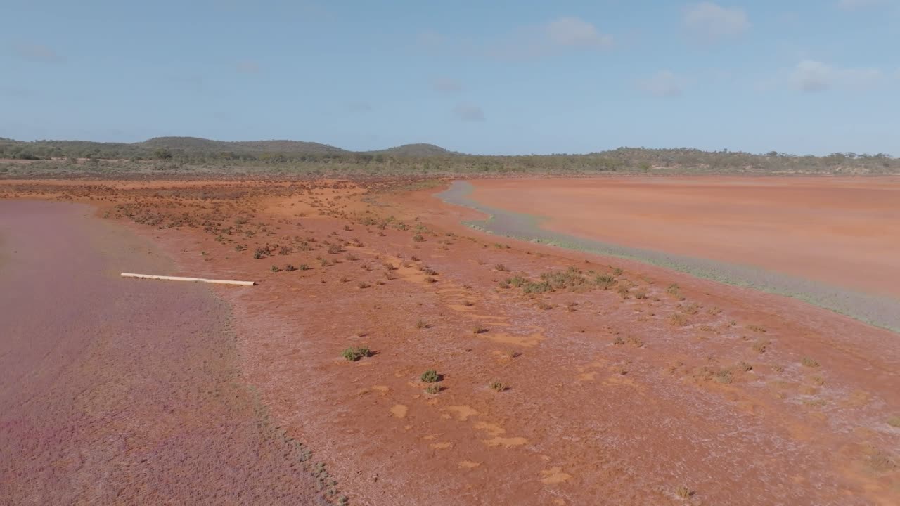 Aerial View of a Vast Red Earth Arid Landscape with Sparse Vegetation and Distant Hills