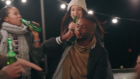 group-of-friends-making-toast-drinking-beer-enjoying-rooftop-party-celebration-at-night-young-multi-ethnic-people-having-fun-socializing-hanging-out-on-weekend