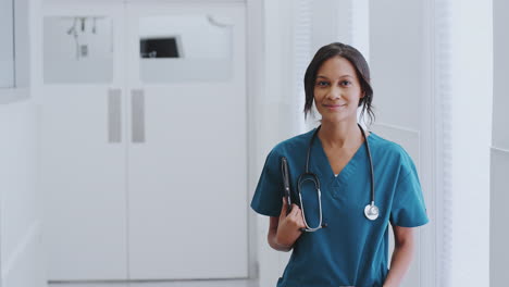 retrato de una doctora con un estetoscopio y trajes en el pasillo del hospital con una tableta digital