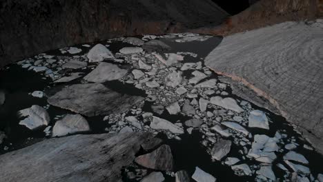 Aerial-flyover-above-the-icebergs-of-a-melting-glacier-in-a-lake-in-remote-parts-of-the-Swiss-Alps-at-dusk