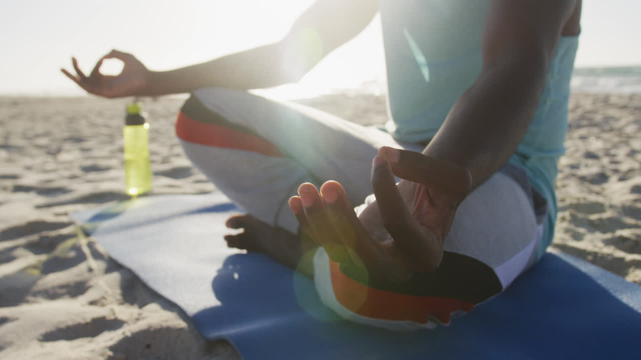 해변에서 요가를 연습하는 아프리카계 미국인 남성의 중간 섹션, 바가에서 야외 운동