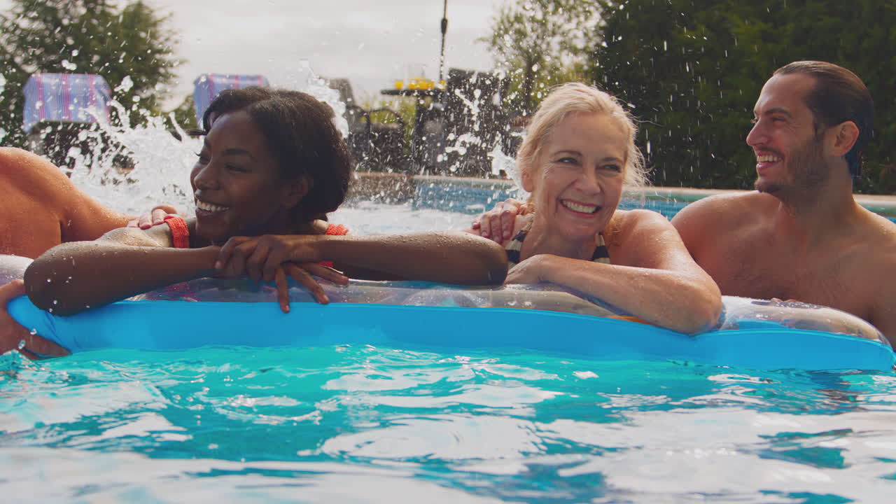Famiglia sorridente con genitori maturi e figli adulti in vacanza estiva, in piscina su un materassino gonfiabile