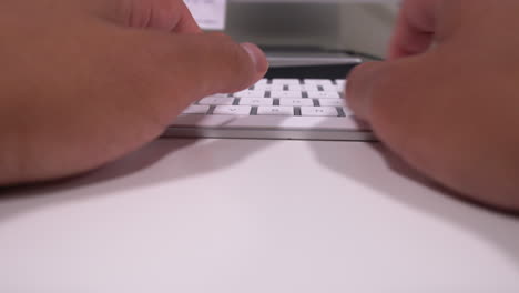 married man's hands typing on keyboard in modern office