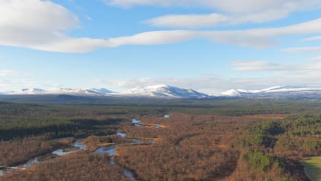 parallax drone shot of snowcapped swedish mountains surrounded by alpine forest and river