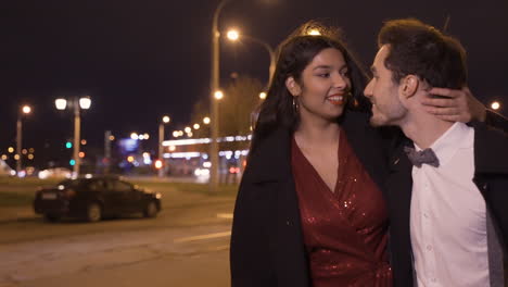 couple wearing stylish clothes hugging while they walking in the street after the new year's party