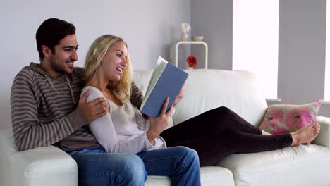 Linda-Pareja-Joven-Leyendo-Juntos-En-El-Sofá-