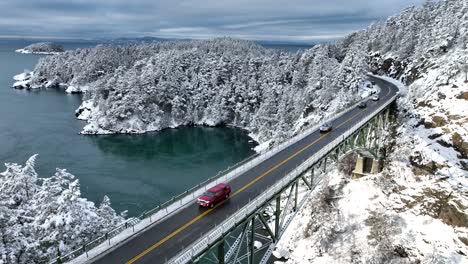 static aerial shot of vehicles passing over deception pass bridge in the snow