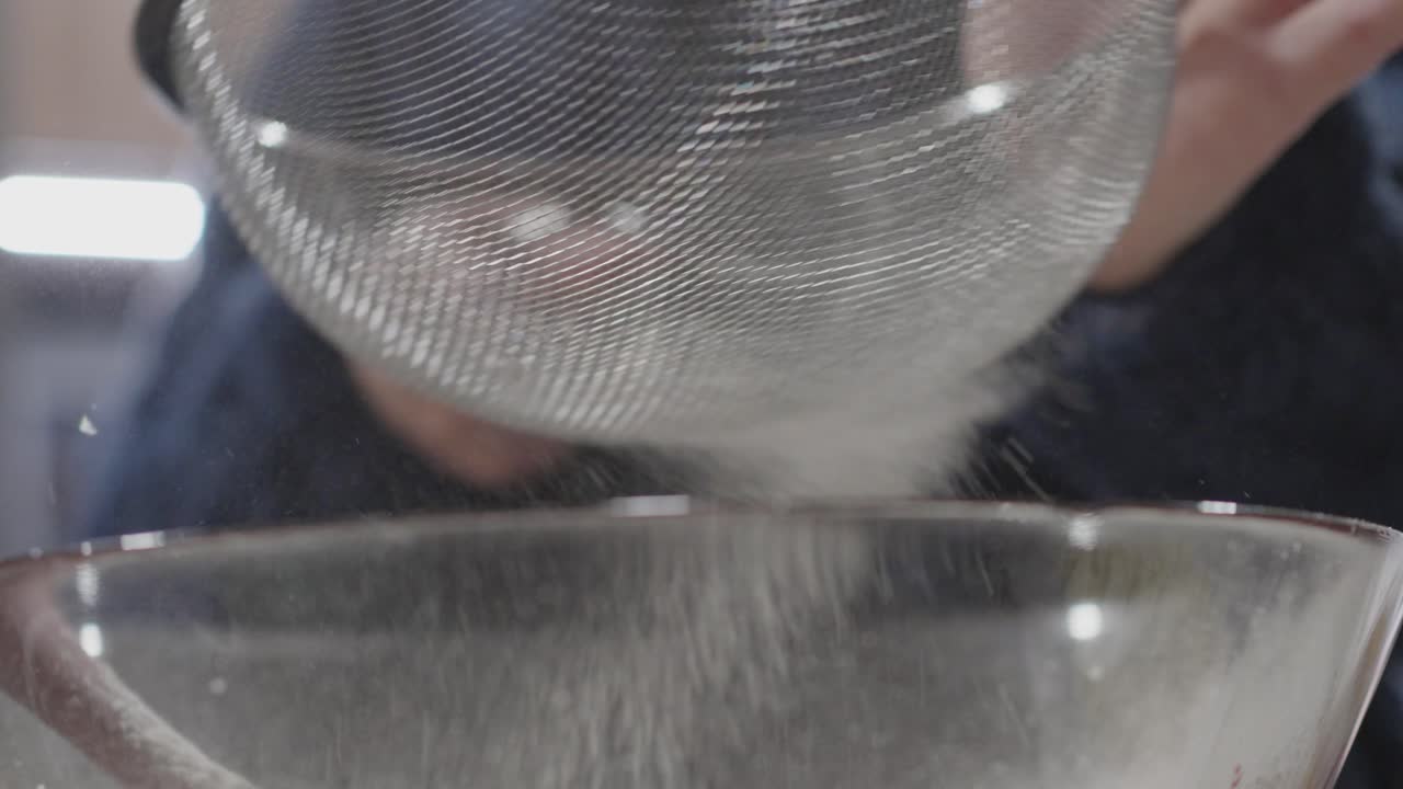 Slow motion Sifting Flour into Red Velvet Cookie Dough in Glass Bowl