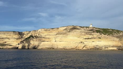 luz del sol en el acantilado del faro de capo pertusato en la isla de córcega visto desde un velero, francia-1