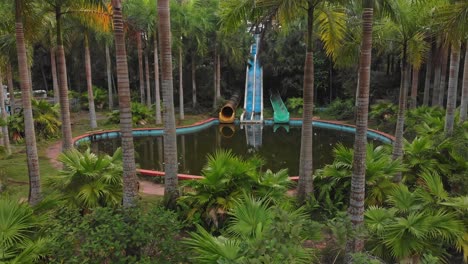 Old-Abandoned-swimming-pool-at-Hue-Vietnam-with-green-vegetation-around,-aerial