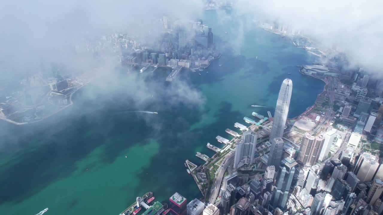 Epic aerial view of the Victoria Harbour in a clear day, with thick cloud and sunlight