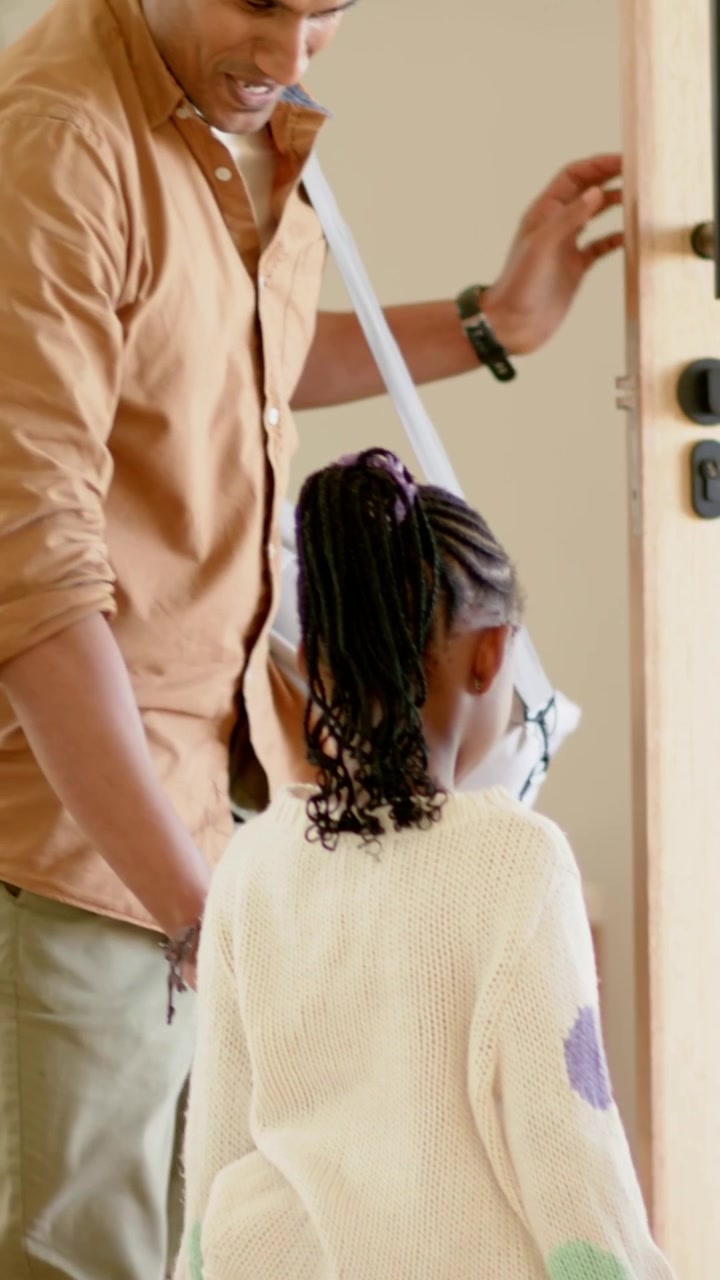 Vertical video: Arriving dad with gray bag at keypad entry, opening door, guiding daughter in dots