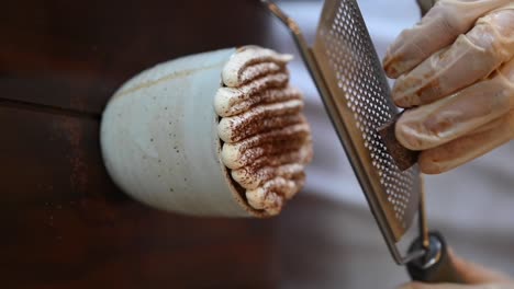 vertical footage: pouring chocolate on the cream coffee latte, close-up of the coffee cup, a drink and dessert combination