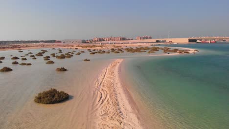 Drone-orbit-circle-shot-over-middle-eastern-sand-bank-ocean-revealing-bridge