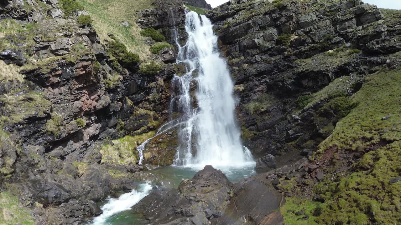 Waterfall in Izas Valley, Aragón, Spain, surrounded by rocky cliffs and green landscape