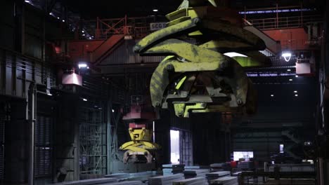 Industrial-crane-operating-in-a-steel-mill-at-night,-glowing-with-artificial-lighting