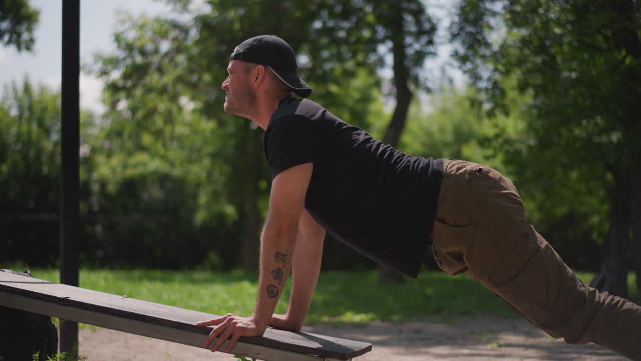 Man Exercises Outdoors, Street Workout Enhances Chest Strength, Person Engaging In Calisthenics Routine In Sunny Park Setting, Man Executes Incline Pushups On Park Bench During Outdoor Fitness Session