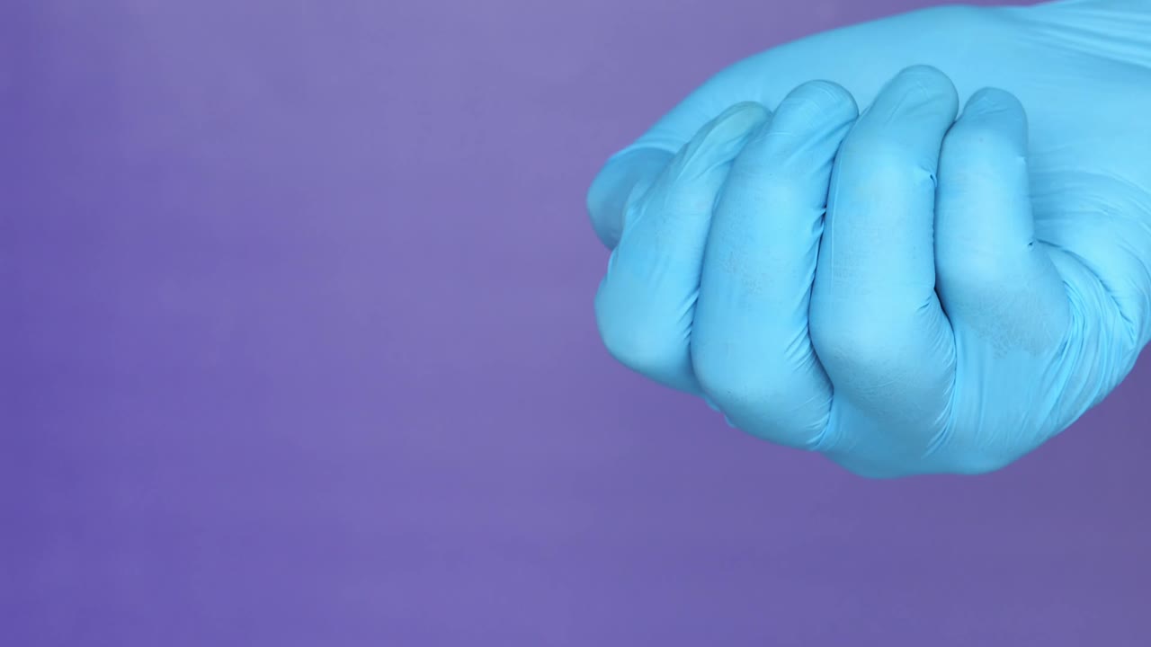 cápsulas azules y blancas en una mano con guante