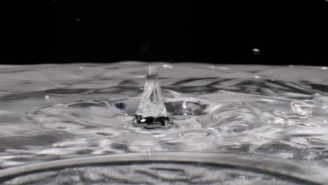 Mehrere-Wassertropfen-Spritzen-Und-Prallen-In-Zeitlupe-Auf-Kristallklare-Flüssigkeit