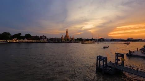 colorful sunset time-lapse at chao phraya river riverside with cruise boats traveling by wat arun temple